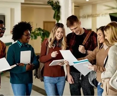 Students holding papers in a college campus hallway